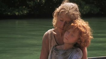 Movie still from “The Mosquito Coast” (1986), directed by Peter Weir – A woman and a child standing next to a body of water; Close Up shot, Low angle