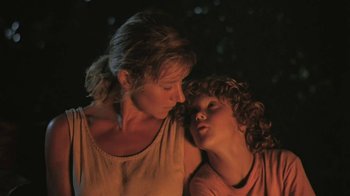 Movie still from “The Mosquito Coast” (1986), directed by Peter Weir – A woman and a child are standing next to each other; Close Up shot, Low angle