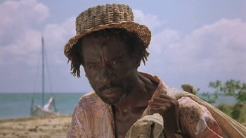 Movie still from “The Mosquito Coast” (1986), directed by Peter Weir – A man in a straw hat is standing on the beach; Close Up shot, Low angle