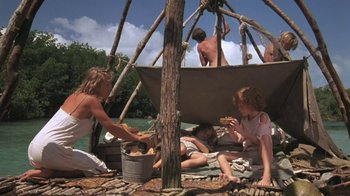 Movie still from “The Mosquito Coast” (1986), directed by Peter Weir – A group of people sitting on a raft in the middle of a river; Wide shot, High angle