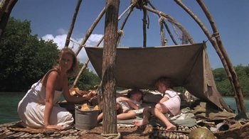 Movie still from “The Mosquito Coast” (1986), directed by Peter Weir – A woman and two children sitting under a shelter; Wide shot, Low angle