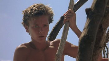 Movie still from “The Mosquito Coast” (1986), directed by Peter Weir – A shirtless man holding a stick in a tree; Close Up shot, Low angle