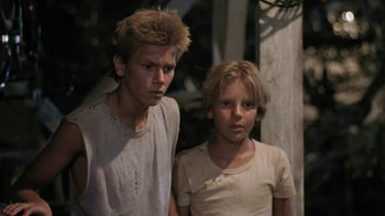 Movie still from “The Mosquito Coast” (1986), directed by Peter Weir – Two young people standing next to each other in a room; Close Up shot, Low angle