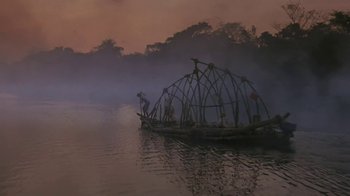 Movie still from “The Mosquito Coast” (1986), directed by Peter Weir – A boat with a bamboo structure in the middle of a lake; Extreme Wide shot, Low angle