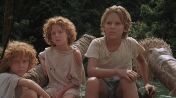 Movie still from “The Mosquito Coast” (1986), directed by Peter Weir – Two young people sitting on a bench in the woods; Medium shot, Low angle