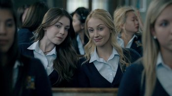Movie still from “The Moth Diaries” (2011), directed by Mary Harron – Two young women in school uniforms looking in the mirror; Medium shot, Over the shoulder angle