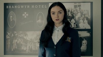 Movie still from “The Moth Diaries” (2011), directed by Mary Harron – A woman in a suit standing in front of a wall; Close Up shot, Over the shoulder angle