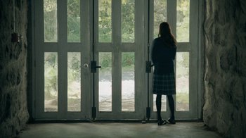 Movie still from “The Moth Diaries” (2011), directed by Mary Harron – A woman standing in front of a pair of doors; Wide shot, High angle