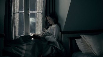 Movie still from “The Moth Diaries” (2011), directed by Mary Harron – A woman sitting in front of a window reading a book; Medium shot, High angle