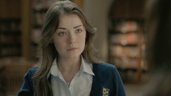 Movie still from “The Moth Diaries” (2011), directed by Mary Harron – A woman with long brown hair wearing a white shirt and a blue jacket; Close Up shot, Over the shoulder angle