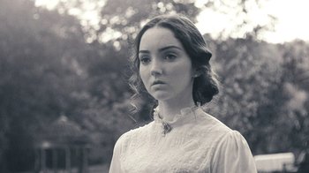 Movie still from “The Moth Diaries” (2011), directed by Mary Harron – A woman in a white dress is standing in a park; Close Up shot, Over the shoulder angle