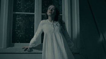 Movie still from “The Moth Diaries” (2011), directed by Mary Harron – A woman standing in front of an open window at night; Medium shot, Low angle
