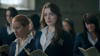 Movie still from “The Moth Diaries” (2011), directed by Mary Harron – A woman with long brown hair wearing a white shirt and a blue jacket; Close Up shot, Over the shoulder angle