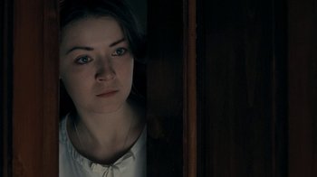 Movie still from “The Moth Diaries” (2011), directed by Mary Harron – A woman with blue eyes standing next to a wooden wall; Close Up shot, Over the shoulder angle
