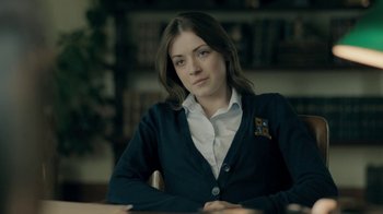 Movie still from “The Moth Diaries” (2011), directed by Mary Harron – A woman sitting at a table in front of a bookshelf; Close Up shot, Over the shoulder angle