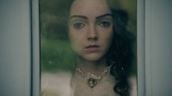 Movie still from “The Moth Diaries” (2011), directed by Mary Harron – A young woman looking out of a glass window; Close Up shot, Overhead angle