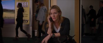 Movie still from “The Mountain Between Us” (2017), directed by Hany Abu-Assad – A woman sitting on the ground talking on a cell phone; Medium shot, High angle