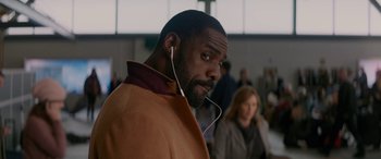 Movie still from “The Mountain Between Us” (2017), directed by Hany Abu-Assad – A man wearing a brown coat and holding a pair of white headphones; Close Up shot, Over the shoulder angle