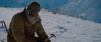 Movie still from “The Mountain Between Us” (2017), directed by Hany Abu-Assad – A man with a hammer in the snow on top of a mountain; Close Up shot, High angle