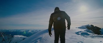 Movie still from “The Mountain Between Us” (2017), directed by Hany Abu-Assad – A man standing on top of a snow covered slope; Wide shot, Low angle