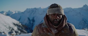 Movie still from “The Mountain Between Us” (2017), directed by Hany Abu-Assad – A man in a brown jacket and a fur hat in front of a snowy mountain; Close Up shot, Low angle