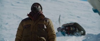 Movie still from “The Mountain Between Us” (2017), directed by Hany Abu-Assad – A man standing in the middle of a snowy field; Medium shot, Low angle