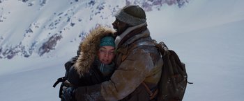 Movie still from “The Mountain Between Us” (2017), directed by Hany Abu-Assad – A man and a woman hugging in the snow; Medium shot, Low angle