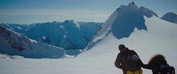 Movie still from “The Mountain Between Us” (2017), directed by Hany Abu-Assad – A man standing on top of a snow covered slope; Extreme Wide shot, High angle