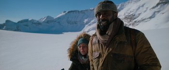 Movie still from “The Mountain Between Us” (2017), directed by Hany Abu-Assad – A man and a woman standing in the snow; Medium shot, Low angle