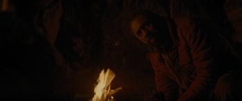 Movie still from “The Mountain Between Us” (2017), directed by Hany Abu-Assad – A man standing in front of a fire at night; Close Up shot, High angle