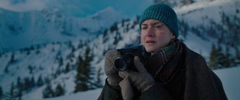 Movie still from “The Mountain Between Us” (2017), directed by Hany Abu-Assad – A woman holding a camera while standing in the snow; Close Up shot, Over the shoulder angle