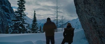 Movie still from “The Mountain Between Us” (2017), directed by Hany Abu-Assad – A man and a woman standing in the snow looking out at the mountains; Wide shot, High angle