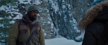 Movie still from “The Mountain Between Us” (2017), directed by Hany Abu-Assad – A man standing in the snow next to a cliff; Medium shot, Low angle