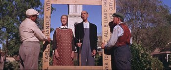 Movie still from “The Music Man” (1962), directed by Morton DaCosta – Two men and a woman standing in front of a building; Medium shot, Low angle
