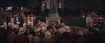 Movie still from “The Music Man” (1962), directed by Morton DaCosta – A group of people sitting in front of a statue of abraham lincoln; Wide shot, High angle