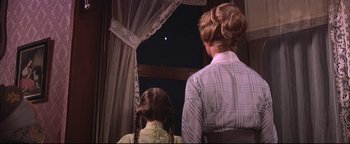 Movie still from “The Music Man” (1962), directed by Morton DaCosta – A woman and a child looking out a window; Medium shot, Low angle