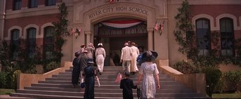 Movie still from “The Music Man” (1962), directed by Morton DaCosta – A group of people walking down the steps of a school; Wide shot, High angle