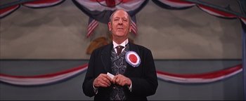 Movie still from “The Music Man” (1962), directed by Morton DaCosta – A man in a suit and tie holding a card; Close Up shot, Low angle