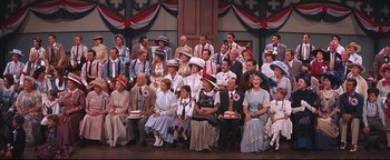 Movie still from “The Music Man” (1962), directed by Morton DaCosta – A large group of people sitting on a stage; Wide shot, High angle