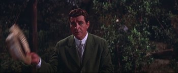 Movie still from “The Music Man” (1962), directed by Morton DaCosta – A man wearing a suit and tie standing in front of a tree; Medium shot, Over the shoulder angle