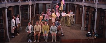 Movie still from “The Music Man” (1962), directed by Morton DaCosta – A group of men sitting on top of a bench; Wide shot, High angle