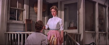 Movie still from “The Music Man” (1962), directed by Morton DaCosta – A woman standing next to a man on a porch; Medium shot, Low angle