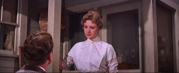 Movie still from “The Music Man” (1962), directed by Morton DaCosta – A woman in a white shirt is standing in front of a mirror; Close Up shot, Over the shoulder angle