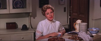 Movie still from “The Music Man” (1962), directed by Morton DaCosta – A woman sitting at a table with a plate of food; Close Up shot, Over the shoulder angle