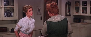 Movie still from “The Music Man” (1962), directed by Morton DaCosta – Two women are talking to each other in a room; Medium shot, Over the shoulder angle