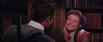 Movie still from “The Music Man” (1962), directed by Morton DaCosta – A man and a woman smiling at each other in front of a book shelf; Close Up shot, Over the shoulder angle