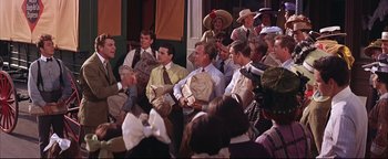 Movie still from “The Music Man” (1962), directed by Morton DaCosta – A group of people sitting in a room; Medium shot, Over the shoulder angle