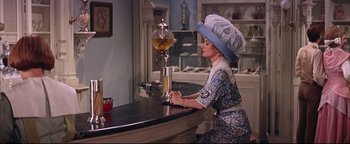 Movie still from “The Music Man” (1962), directed by Morton DaCosta – A woman sitting at a bar wearing a hat; Medium shot, Over the shoulder angle
