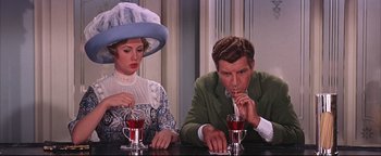 Movie still from “The Music Man” (1962), directed by Morton DaCosta – A man and a woman sitting at a table with drinks; Medium shot, High angle