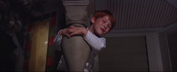 Movie still from “The Music Man” (1962), directed by Morton DaCosta – A young boy leaning against a pillar with his hands on his chest; Medium shot, Low angle